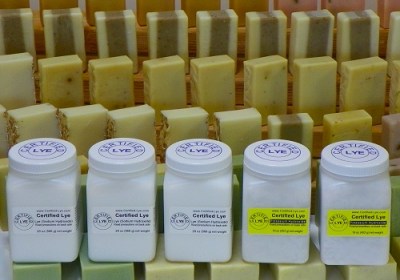 Canisters of Certified Lye sodium hydroxide and potassium hydroxide posing with bars of handmade soap.